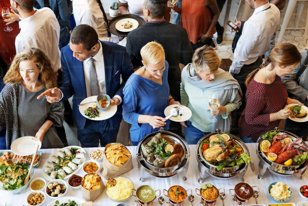 Professional corporate event catering buffet with guests enjoying freshly prepared food and live service by expert caterers